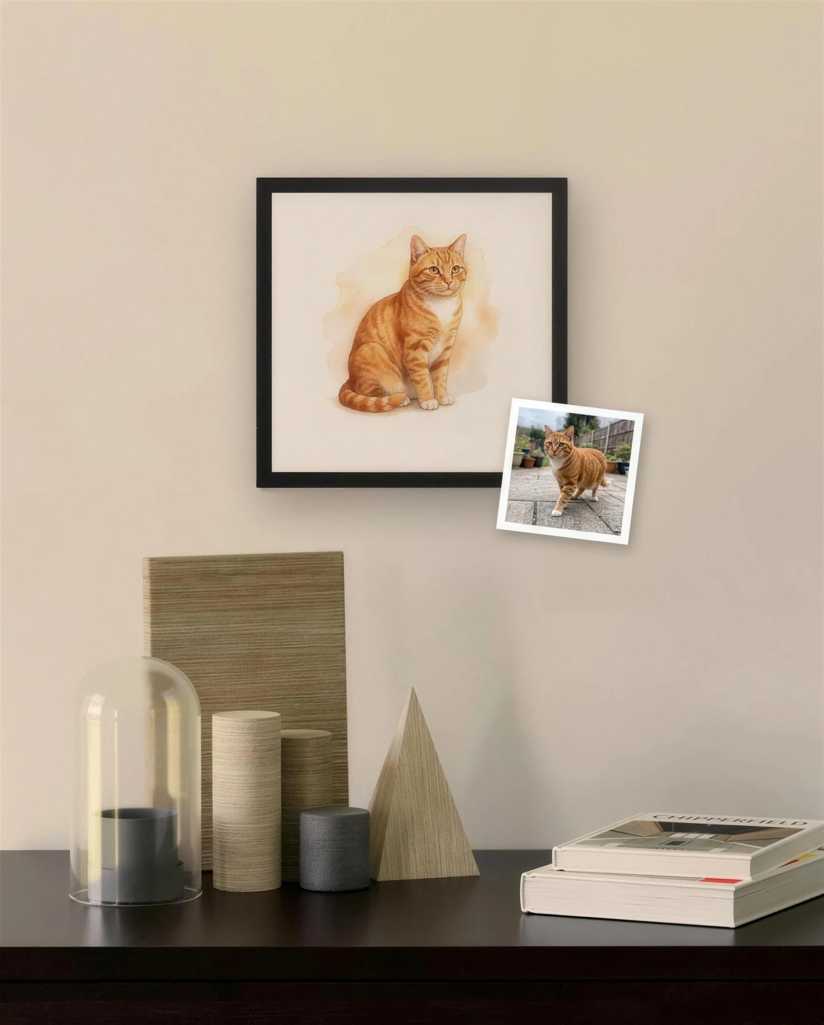 The ginger cat’s portrait in a black frame above a dresser, with a phone photo tucked into the corner of the frame